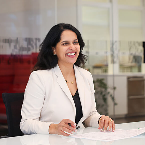 Vandana sits at a table smiling